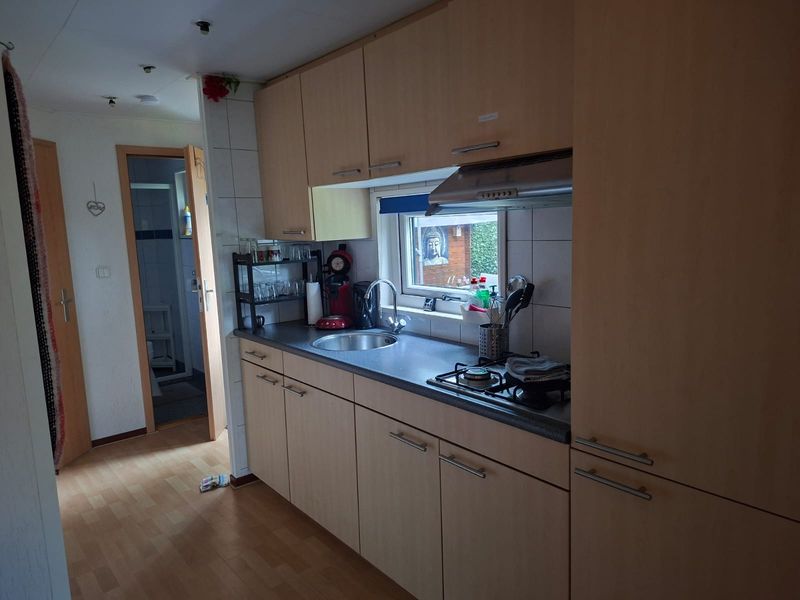 Keuken met lichte kastjes, kookplaat en spoelbak