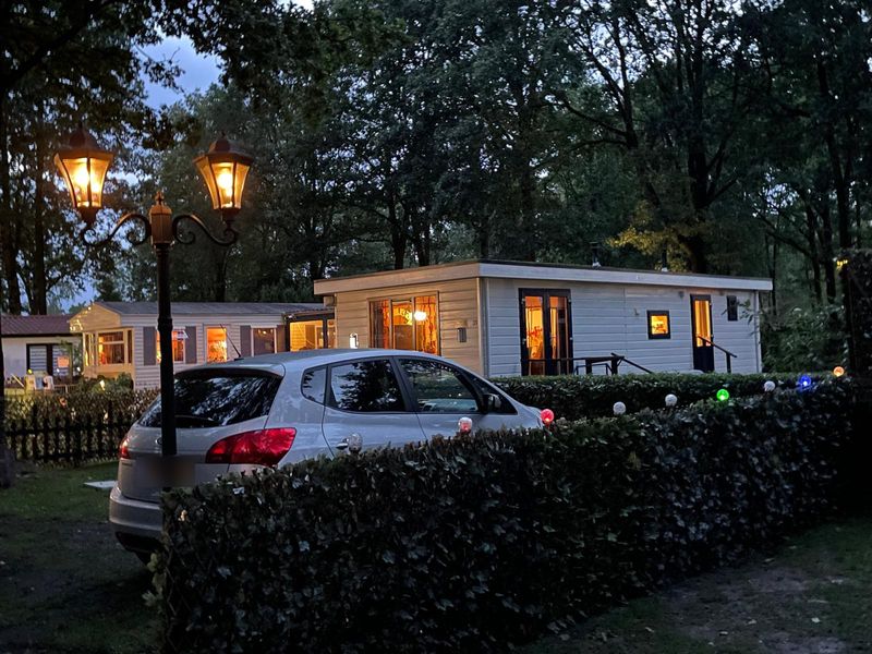 Het verlichte chalet in de avond, met een auto geparkeerd naast het huisje