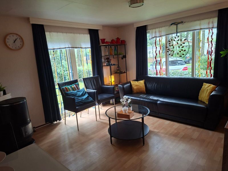 Zithoek met zwarte bank, twee fauteuils en grote ramen